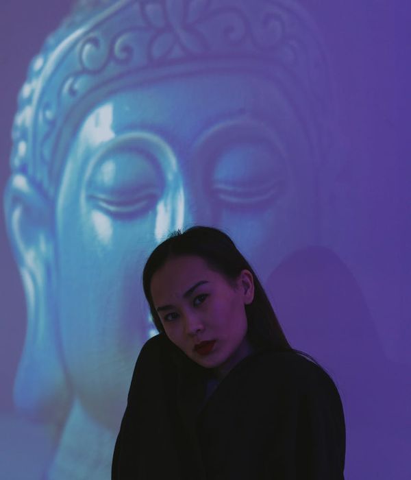 Woman in a calm meditative pose against a serene background.